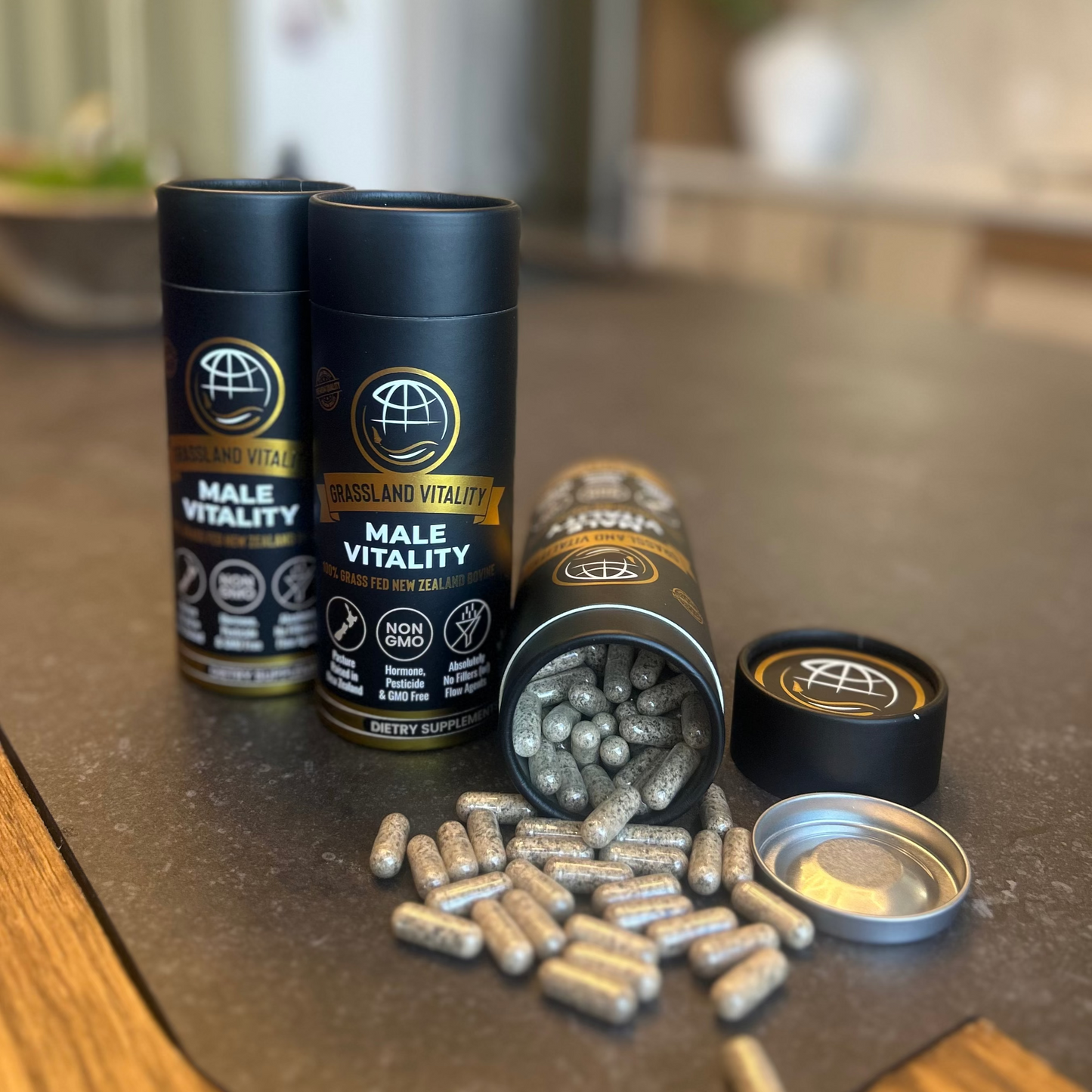 Two black cylindrical containers labeled 'Male Vitality' with their lids off, revealing capsules on a kitchen counter.